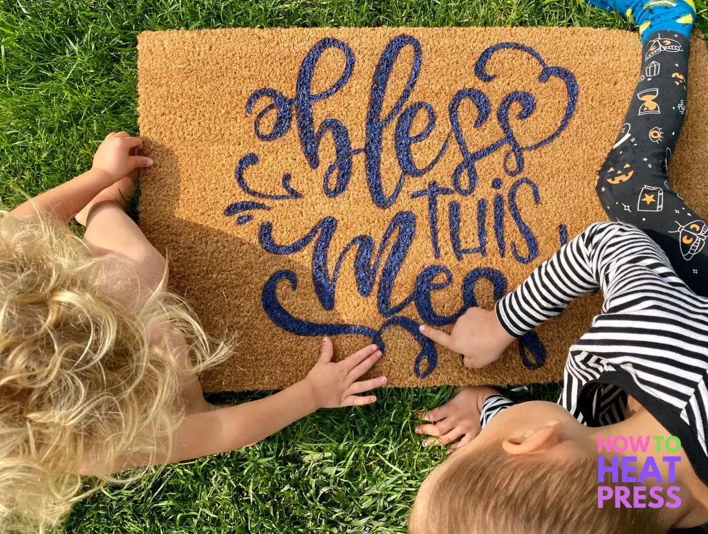 brown doormat with blue 'bless this mess' writing