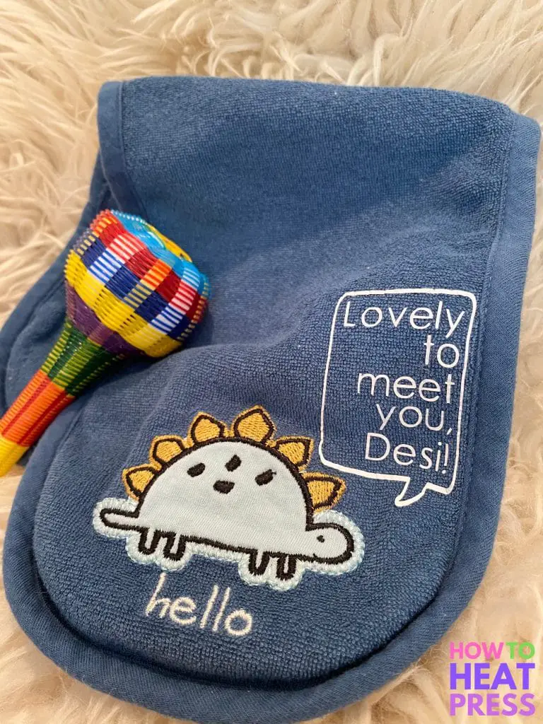 blue burp cloth with dinosaur saying 'lovely to meet you, desi' in white htv