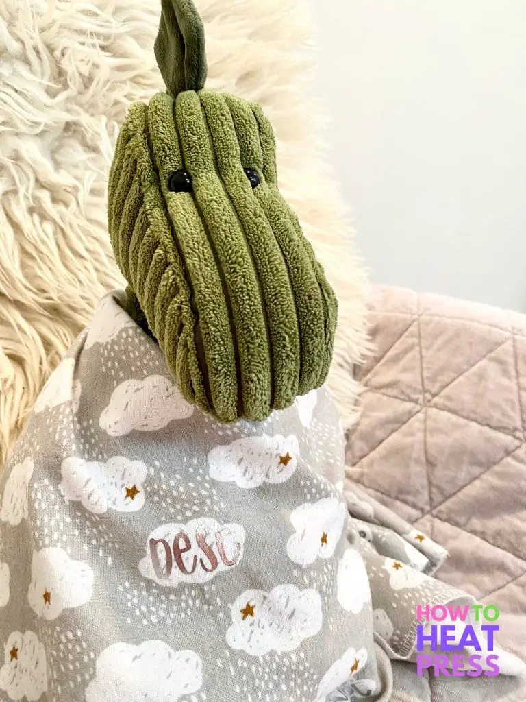 green dinosaur swaddled in gray baby blanket with clouds and baby name