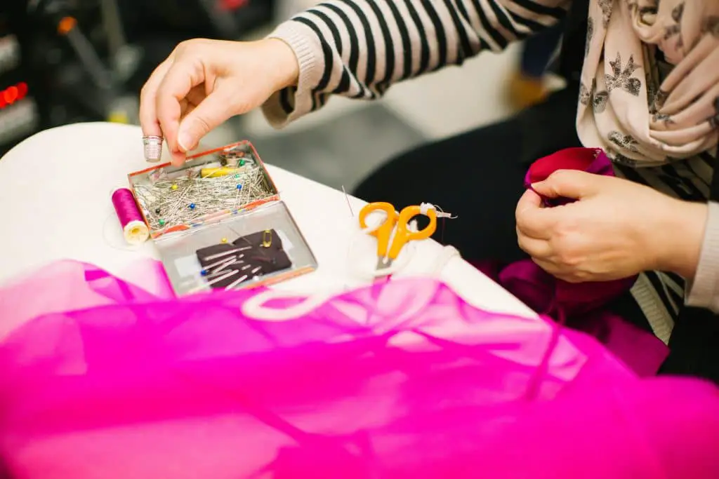 sewist preparing pink fabric project with pins and scissors