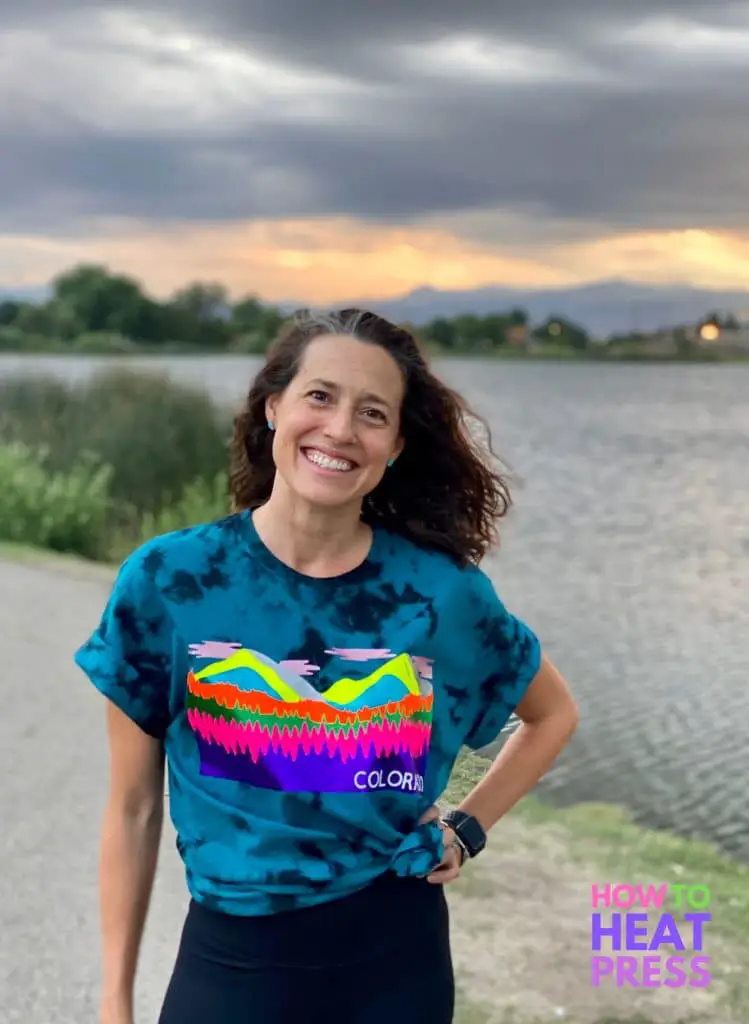 woman wearing shirt with layered htv design standing in front of mountains and lake