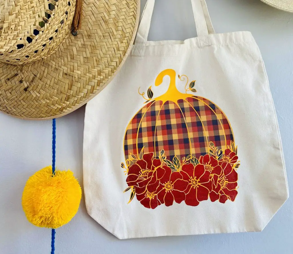 white bag with plaid pumpkin and red flower design